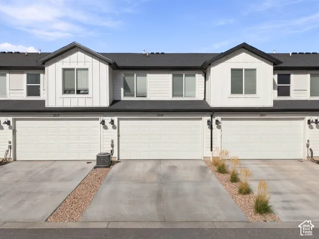 Multi-unit residential exterior featuring board-and-batten siding, shingled rooflines, and individual multi-car garages with concrete driveways