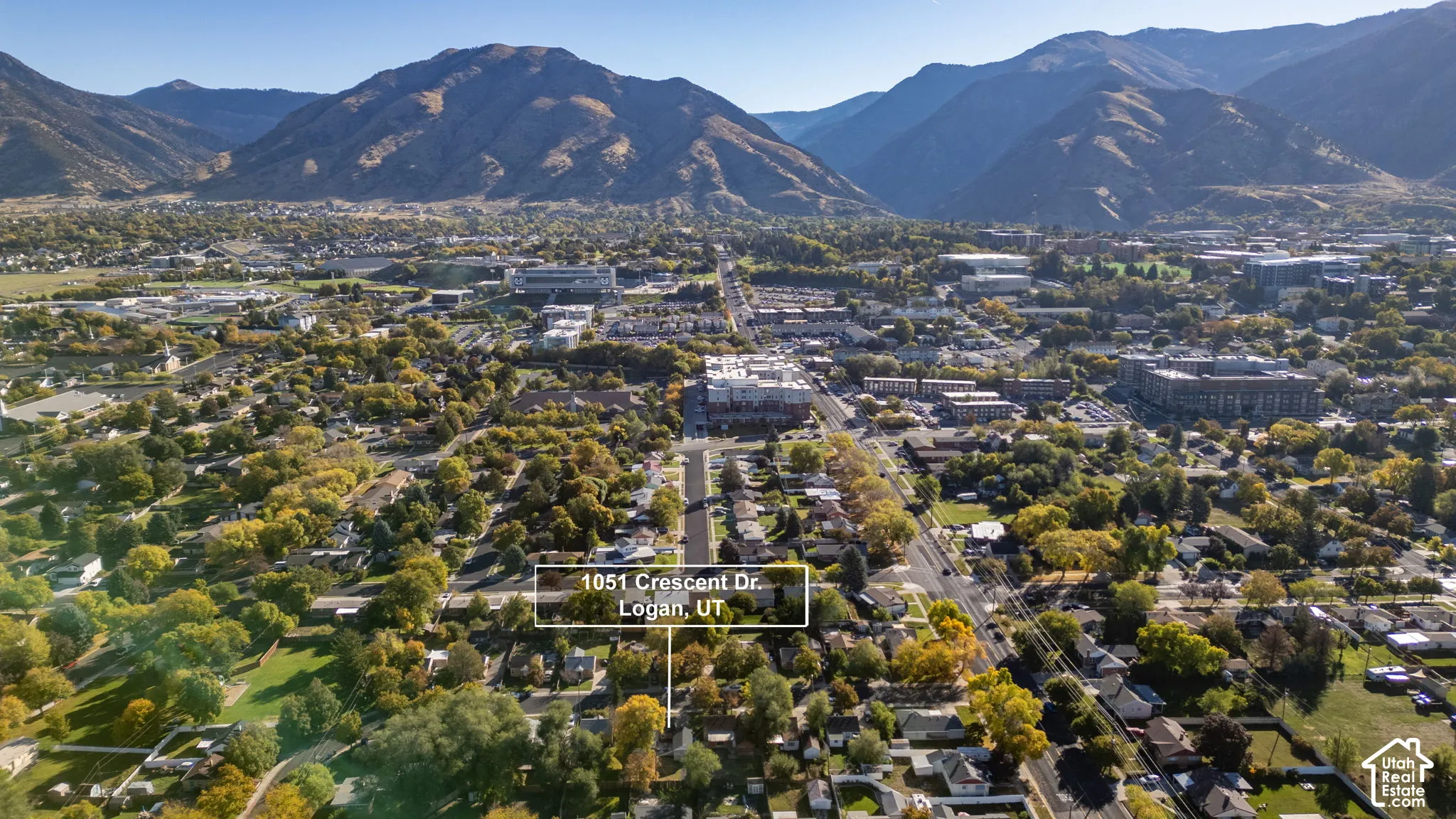 Aerial perspective of Logan, Utah, featuring mountainous topography and mature neighborhood canopy