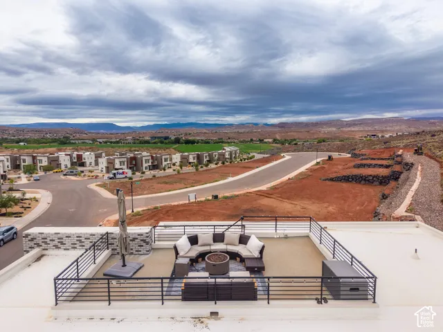 Rooftop terrace featuring black metal railings, a stone-accented perimeter wall, and an expansive mountain backdrop
