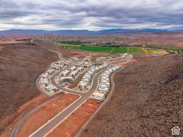 Aerial perspective of a multi-unit residential community featuring contemporary architectural design, paved thoroughfares, and high-desert terrain with mountain backdrops
