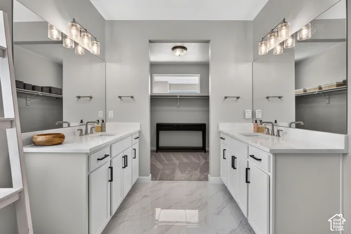 Dual vanities featuring white cabinetry, solid-surface countertops with integrated sinks, matte black hardware, and oversized wall-to-wall mirrors