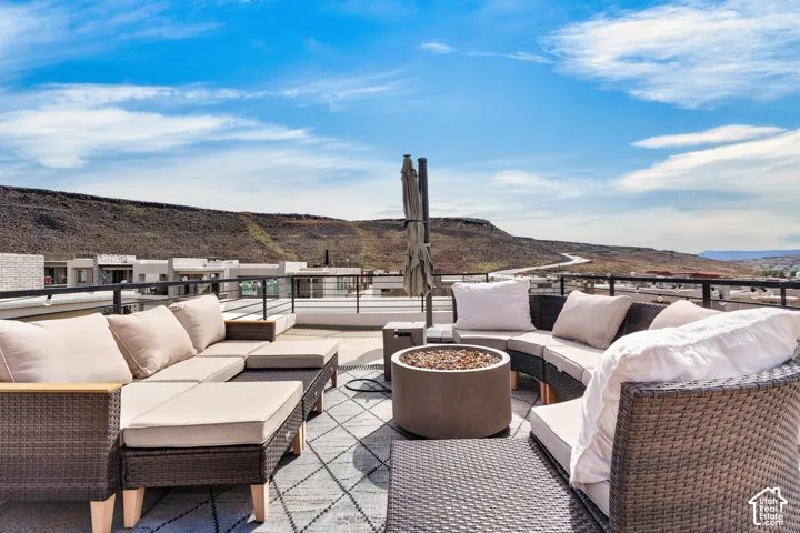 Rooftop terrace featuring a concrete surface, metal perimeter railing, and a permanent cylindrical fire pit
