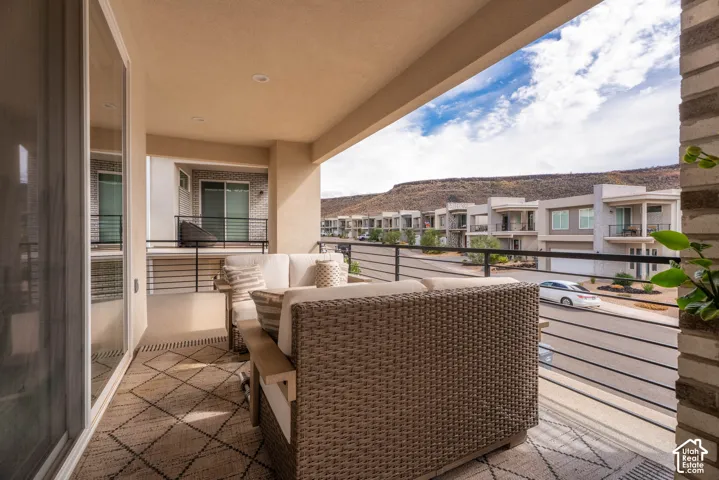 Covered balcony featuring recessed lighting, horizontal metal railings, concrete flooring, and a backdrop of mountain scenery