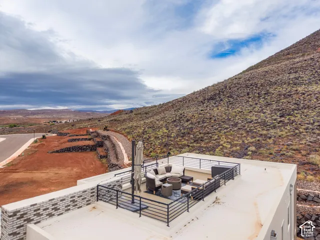 Rooftop deck featuring a metal railing enclosure, brick masonry detailing, and direct mountain backdrop