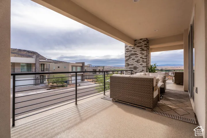 Covered balcony with a brick masonry pillar, horizontal metal railing, and textured concrete flooring
