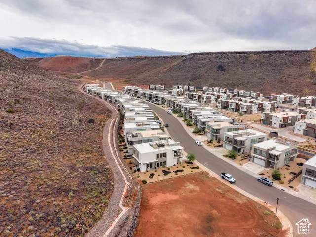 Aerial perspective of modern residential structures featuring flat rooflines, multi-level balconies, and stucco exteriors situated against a prominent mountainous terrain