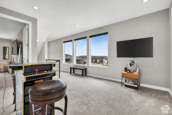 Neutral-toned interior space featuring expansive windows, recessed lighting, and wall-to-wall carpeting