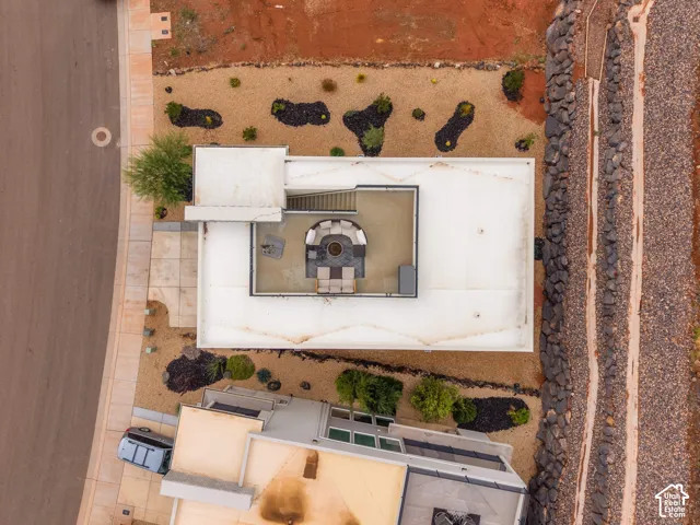 Aerial view of a flat-roof residence featuring a rooftop terrace, metal railings, and xeriscaped ground-level landscaping