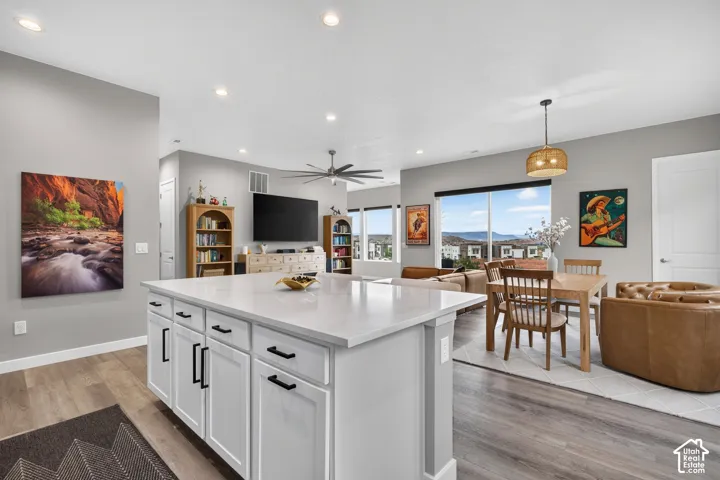 Center island with a stone countertop, wood-finish flooring, recessed lighting, and large windows