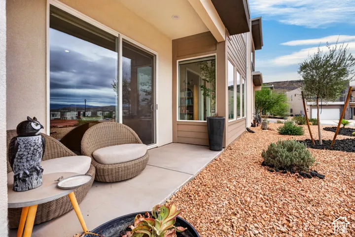 Covered concrete patio featuring floor-to-ceiling windows, sliding glass doors, and desert-inspired landscape with crushed gravel and mature plantings