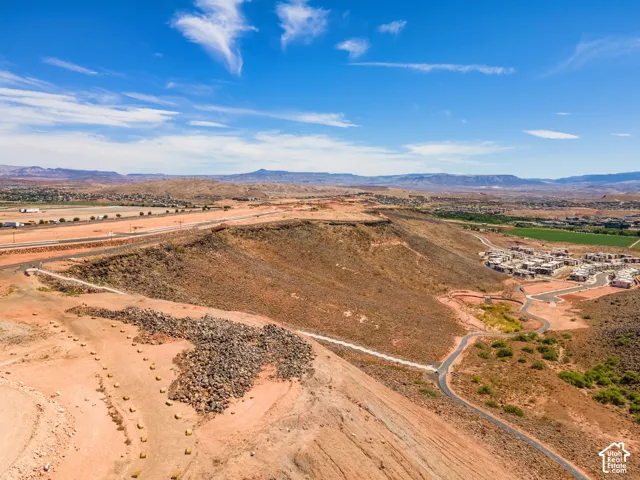 Aerial landscape featuring elevated desert terrain, paved winding roadways, and distant mountain ranges