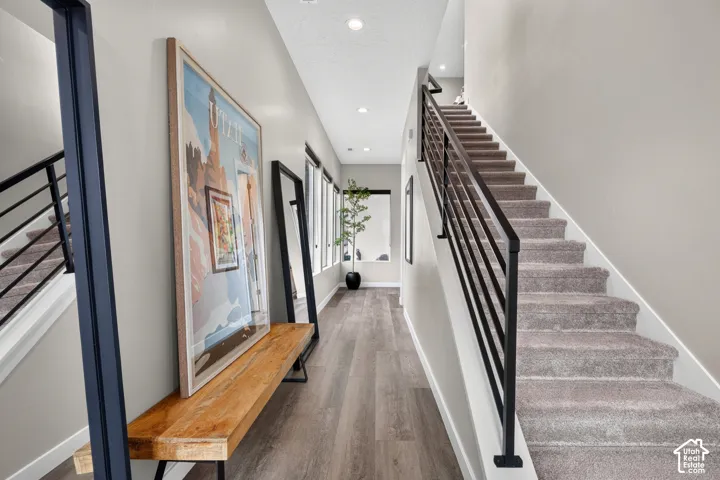 Staircase featuring a matte black metal railing, wood-finish flooring, recessed lighting, and multiple windows