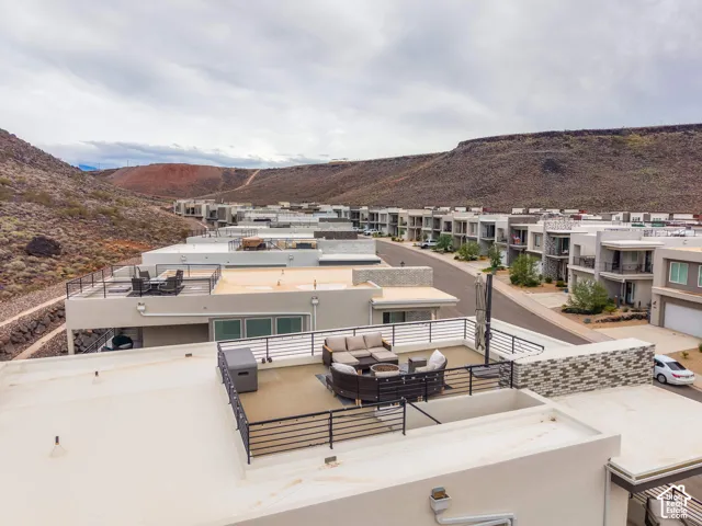 Rooftop terrace with horizontal metal railing, featuring a stone veneer accent wall and desert landscape backdrop