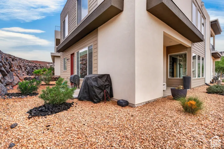 Contemporary exterior featuring multi-textured siding, stucco finishes, large-format glass windows, recessed structural overhangs, and xeriscaped grounds with decorative rock mulch