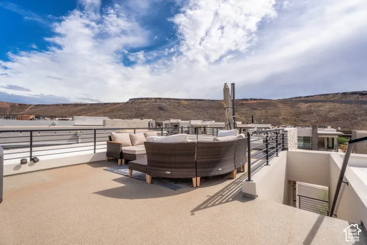 Rooftop terrace featuring a textured concrete surface, metal horizontal-bar railing, and a desert mountain backdrop