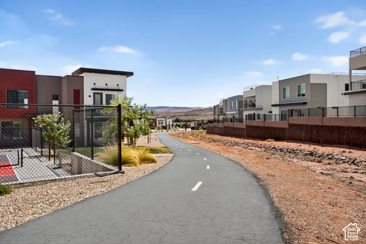 Paved multi-use trail lined by modern residential architecture featuring stucco exteriors, flat rooflines, and iron fencing