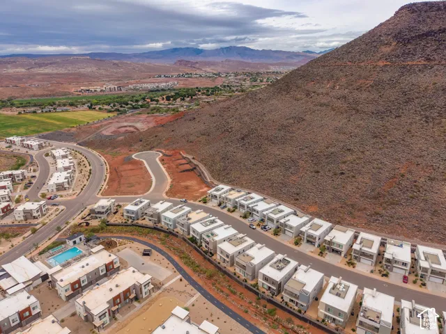 Aerial perspective of a multi-residential community featuring contemporary two-story architecture, concrete-paved street infrastructure, desert landscape, and proximity to mountain terrain