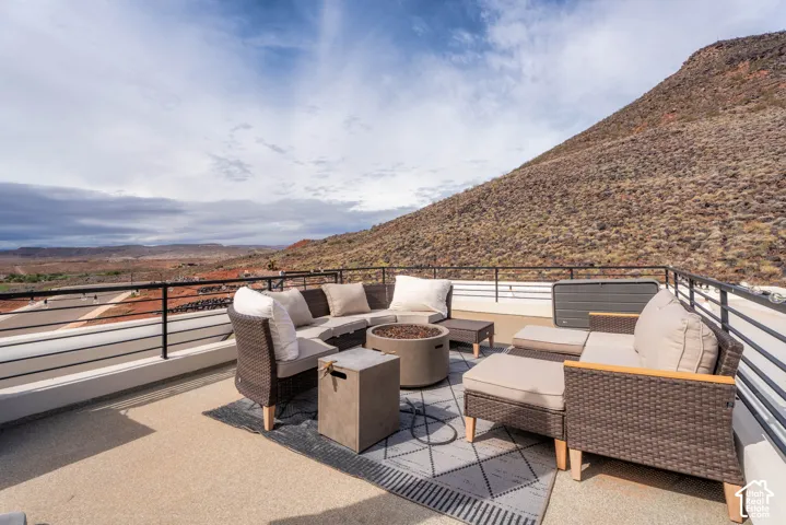 Rooftop terrace featuring a textured concrete surface, black metal railing, and an integrated built-in fire feature