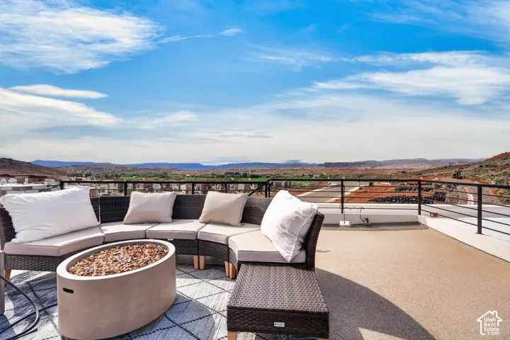 Rooftop terrace featuring a textured concrete surface, metal railing, and built-in stone fire pit