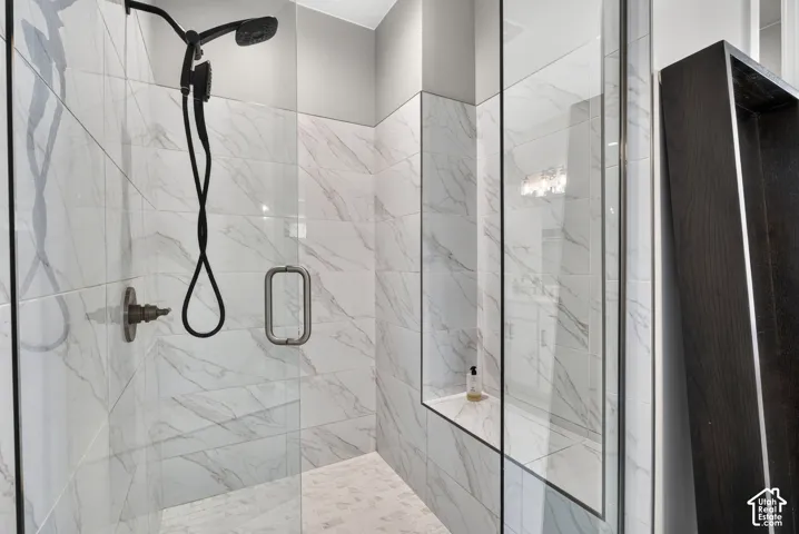 Walk-in shower featuring large-format stone-patterned wall tile, a frameless glass enclosure, a built-in tiled niche, and matte black shower fixtures