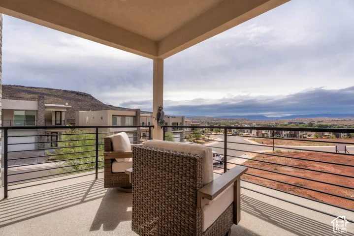 Covered balcony featuring concrete flooring and a black metal railing, showcasing mountain scenery