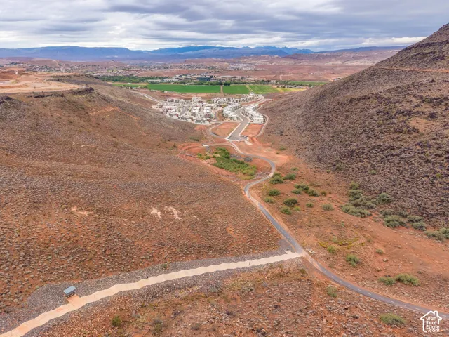 Aerial perspective featuring high-desert topography, paved thoroughfare, and expansive mountain range scenery