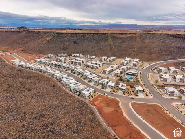 Aerial perspective of a multi-unit residential community featuring contemporary architecture, paved thoroughfares, arid-climate landscaping, and a central swimming pool