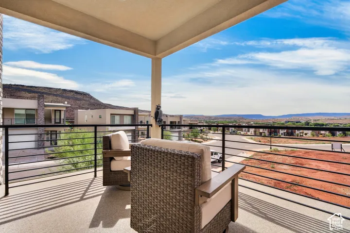 Covered balcony featuring concrete flooring, black metal railing, and mountain backdrop