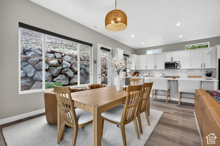 Kitchen featuring white cabinetry, solid-surface countertops, recessed lighting, and wood-finish flooring, with a large picture window showcasing a stone retaining wall