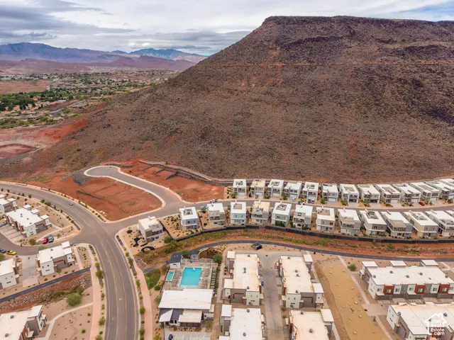 Aerial perspective showcasing a community with an outdoor swimming pool, paved streets, and mountainous terrain