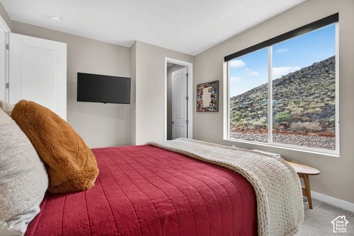 Neutral-toned room featuring a large picture window, high-profile natural scenery, wall-mounted television bracket, and neutral carpeting