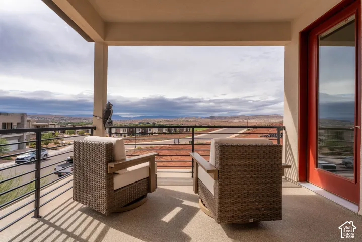 Covered balcony featuring concrete flooring, a horizontal metal railing system, and red-finished door frame