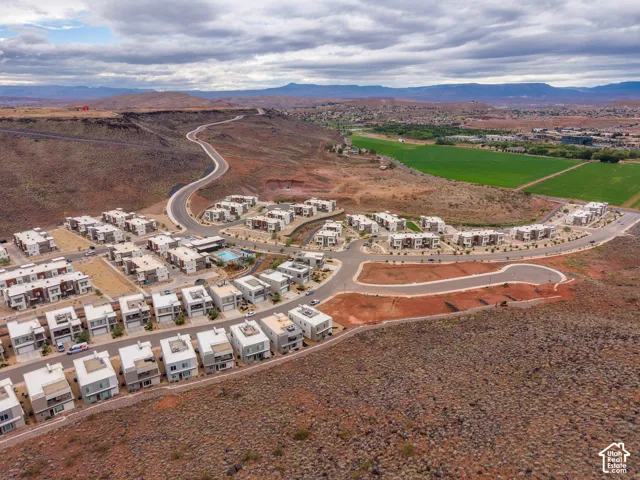 Aerial perspective featuring multi-story residential structures, paved asphalt roads, mountain scenery, and a community swimming pool