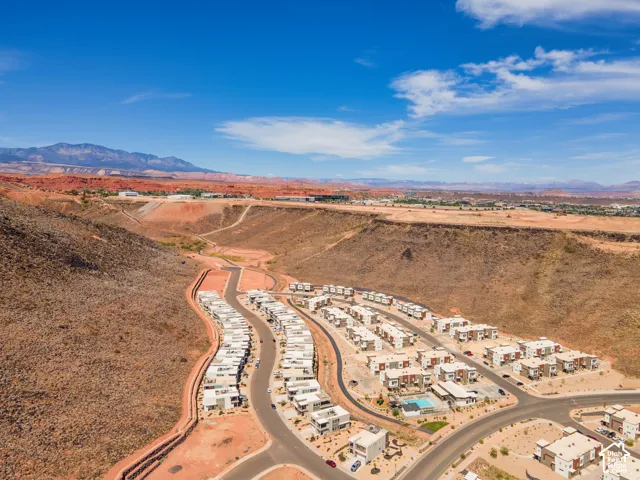 Aerial perspective of a multi-unit residential community situated within a desert landscape featuring prominent mountain backdrops and expansive natural terrain