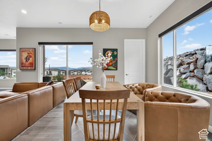 Open-concept interior featuring wood-finish flooring, sliding glass doors, large picture windows, a textured pendant light fixture, and an exterior stone retaining wall