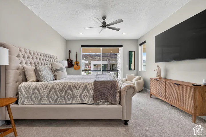 Bedroom featuring neutral carpeting, a ceiling fan with integrated lighting, recessed lighting, sliding glass doors, and a mountain backdrop