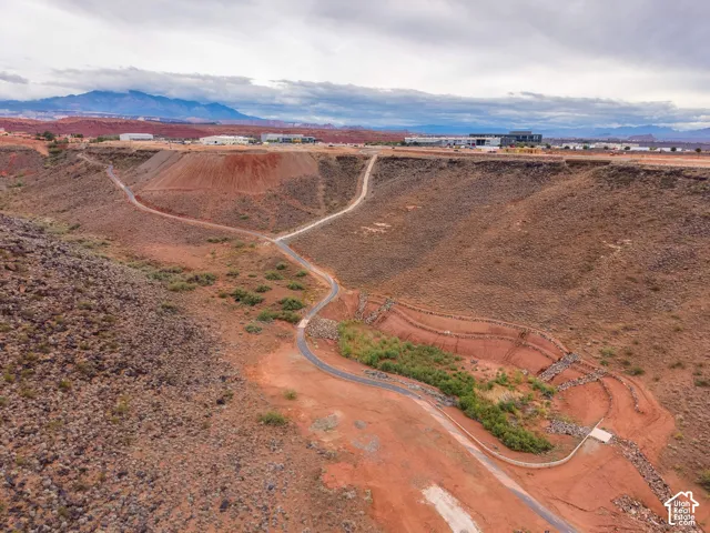 Aerial perspective featuring native desert terrain, paved walking path, stone-retaining walls, and mountain backdrop