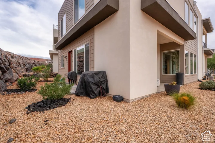 Exterior featuring mixed stucco and lap siding, cantilevered roofline, covered patio, and desert-inspired landscape with rock mulch