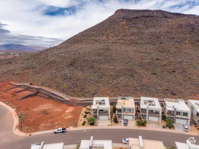 Modern residential community featuring multi-level structures with flat roof terraces, attached garages, and prominent mountain backdrop