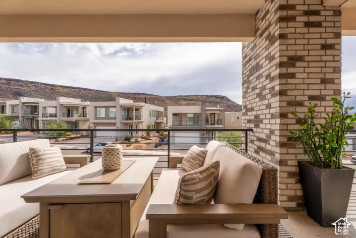 Covered balcony featuring a decorative brick column, horizontal metal railing, and mountain backdrop