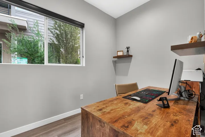 Room featuring large slider window, wood-finish flooring, and two wall-mounted floating shelves