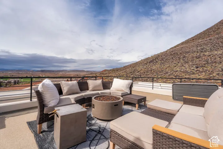 Expansive rooftop terrace featuring a stone-texture floor finish, metal railings, and a mountainous backdrop
