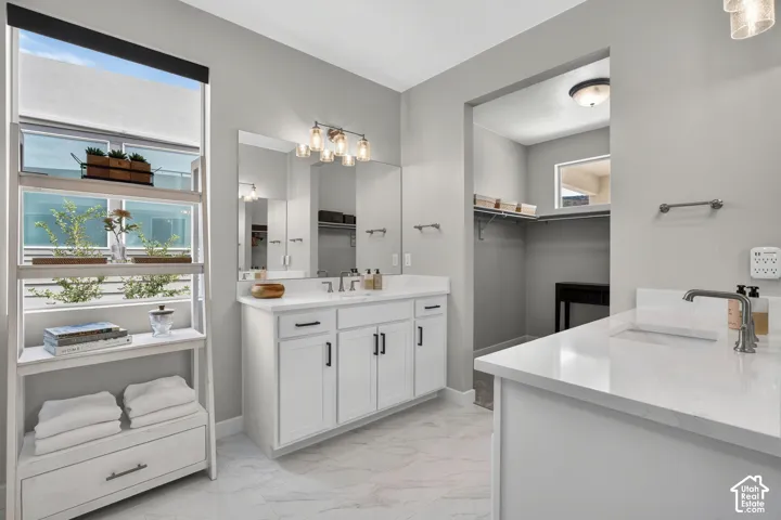 Double vanity featuring white cabinetry, quartz countertops, undermount sinks, and matte black hardware, accented by large-format tile flooring