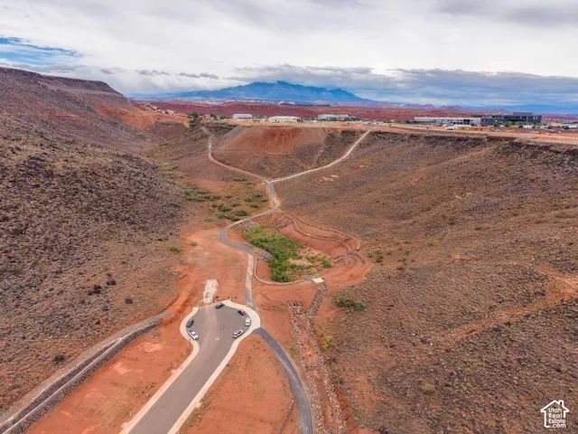 Aerial perspective featuring paved asphalt roads, concrete curbing, and expansive natural desert terrain set against a prominent mountain backdrop