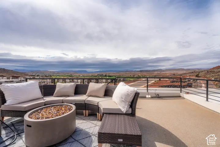 Elevated outdoor deck with horizontal metal railing, textured stone-finish flooring, and expansive desert mountain backdrop