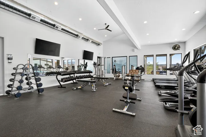 Fitness center featuring recessed lighting, vaulted ceilings, rubber flooring, industrial exposed ductwork, and wall-to-wall mirrors