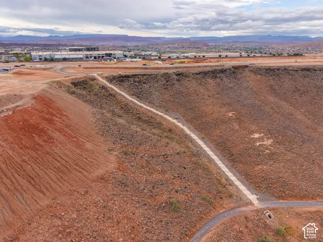 Aerial perspective featuring expansive desert topography, a paved multi-use trail, and prominent mountain backdrops