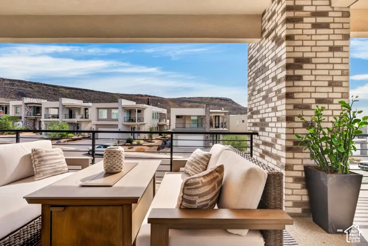 Covered balcony featuring a multi-tonal brick column, black metal railing, and mountain backdrop