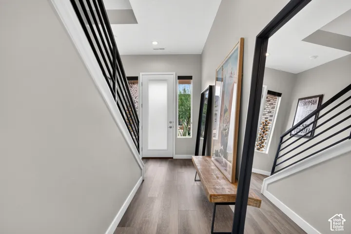 Entryway featuring wood-finish flooring, metal staircase railings, recessed lighting, and a frosted glass-paneled entry door
