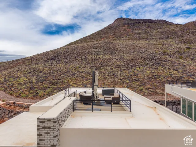 Rooftop deck with horizontal metal railing, brick-accented wall, and prominent mountain backdrop